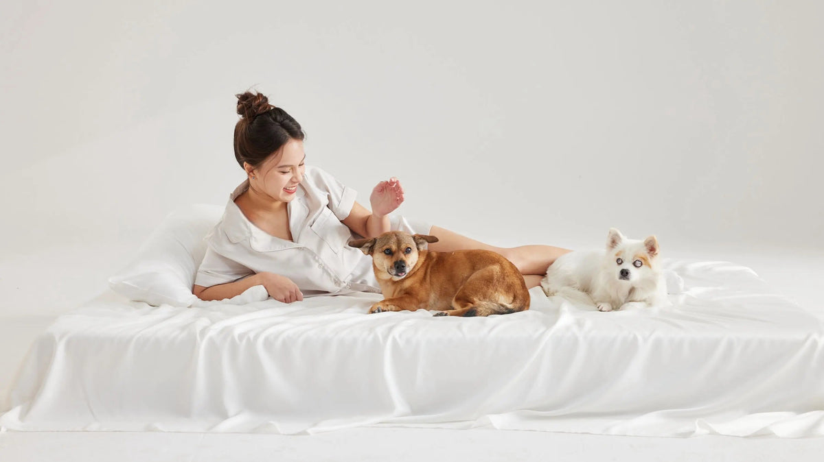 Woman sitting with two dogs on white Furify bedding