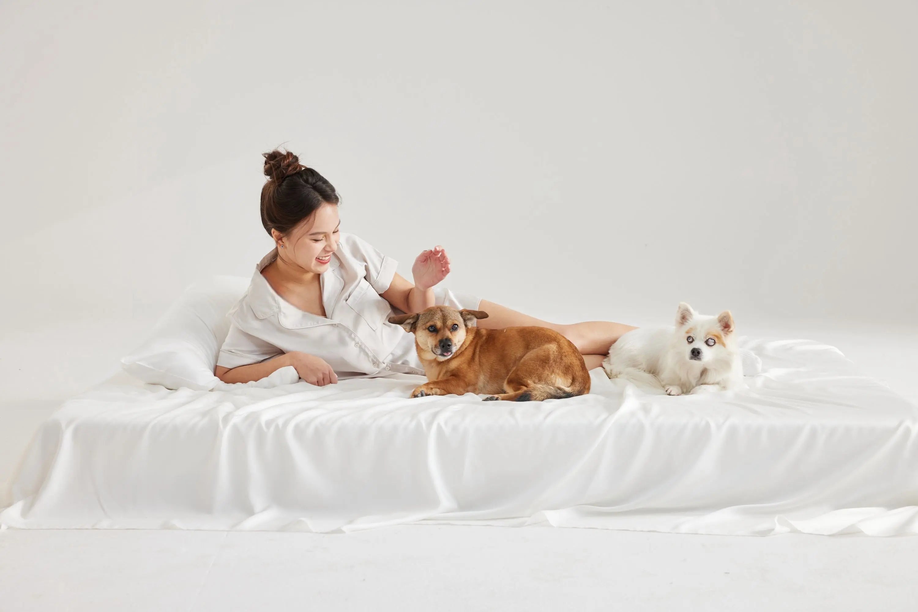 Woman sitting with two dogs on white Furify bedding